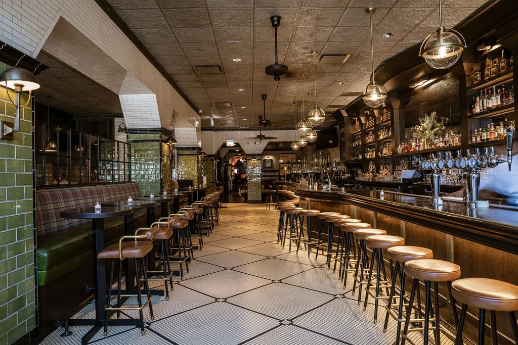Interior of a sophisticated bar with a long bar and booth seating.