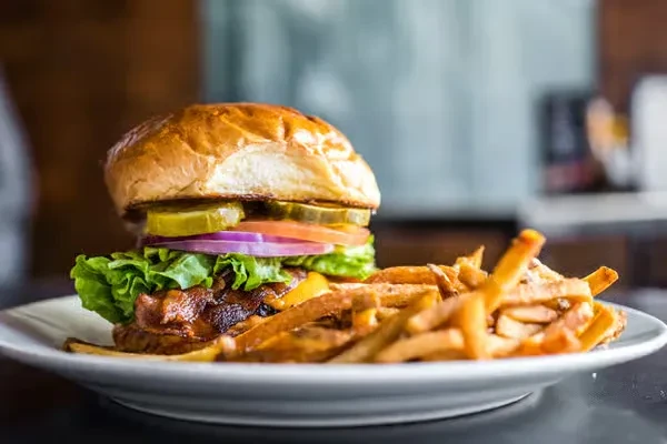 Gourmet burger and golden french fries on a white plate.