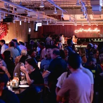 A lively, crowded bar with people socializing under dim lights.