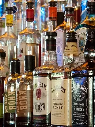 Close-up of numerous, clearly labeled liquor bottles behind a bar.