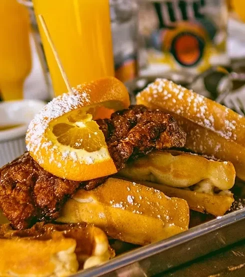 Chicken and waffles or French toast on a metal tray.