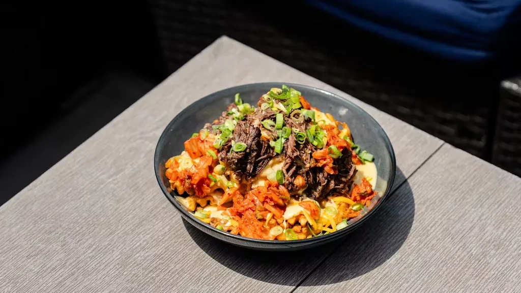 Fries topped with pulled beef, kimchi, cheese sauce, and green onions.