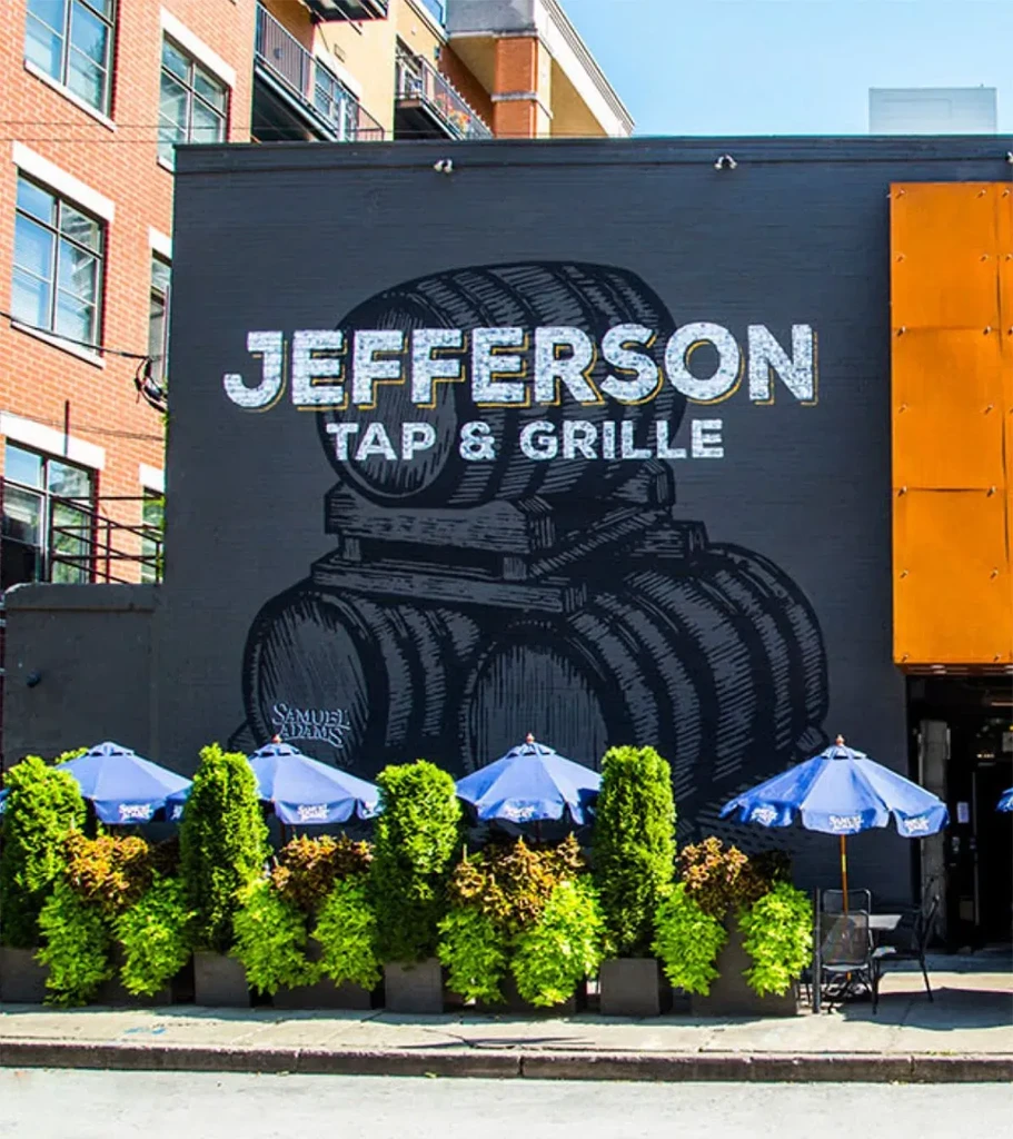 Exterior of Jefferson Tap & Grille with a mural and outdoor seating.