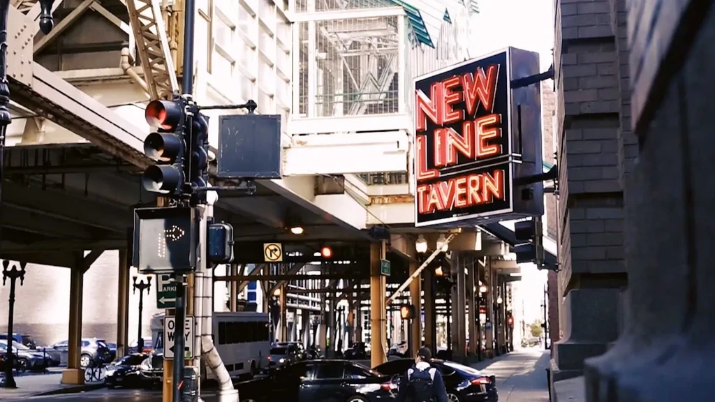 Street scene with elevated train tracks and "NEW LINE TAVERN" sign.