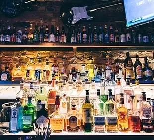 Well-stocked bar with numerous liquor bottles and a brick wall.