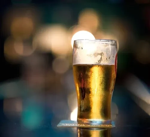Close-up of a cold glass of golden beer with condensation.