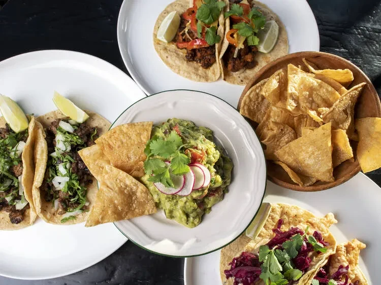 Overhead shot of various tacos, guacamole, and tortilla chips.