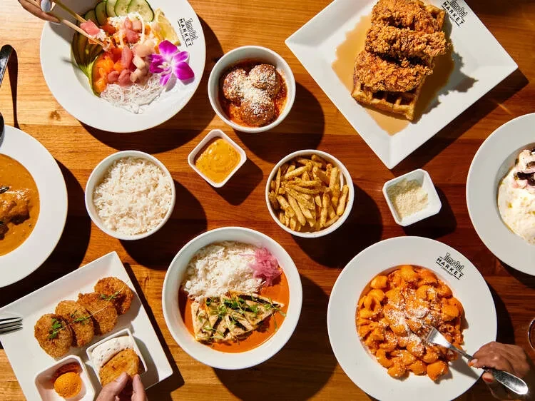 Overhead view of a wooden table full of various colorful dishes.