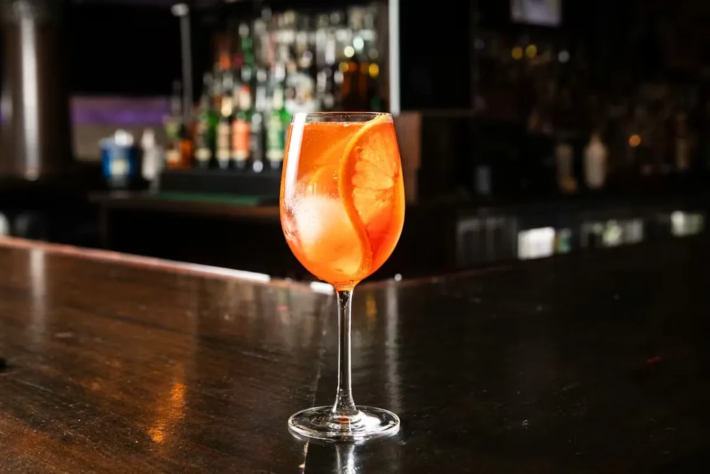 Orange cocktail in a wine glass with an orange slice.