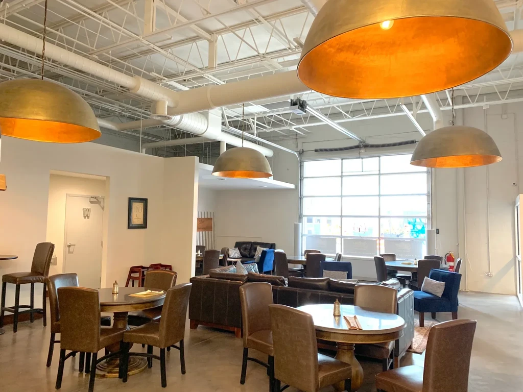 Interior of an empty industrial-chic restaurant with diverse seating options.