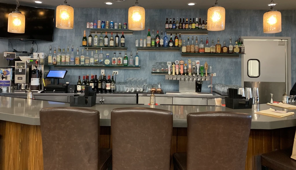 Modern bar area with stocked shelves, beer taps, and coffee station.
