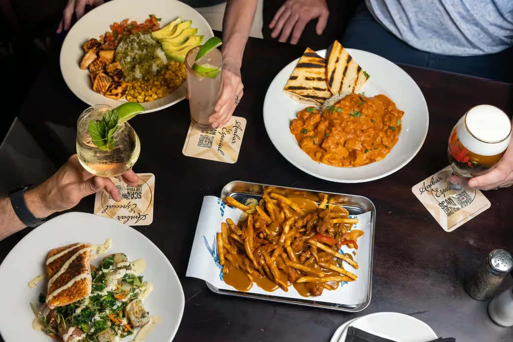 Overhead shot of a table with multiple dishes and hands reaching for food.