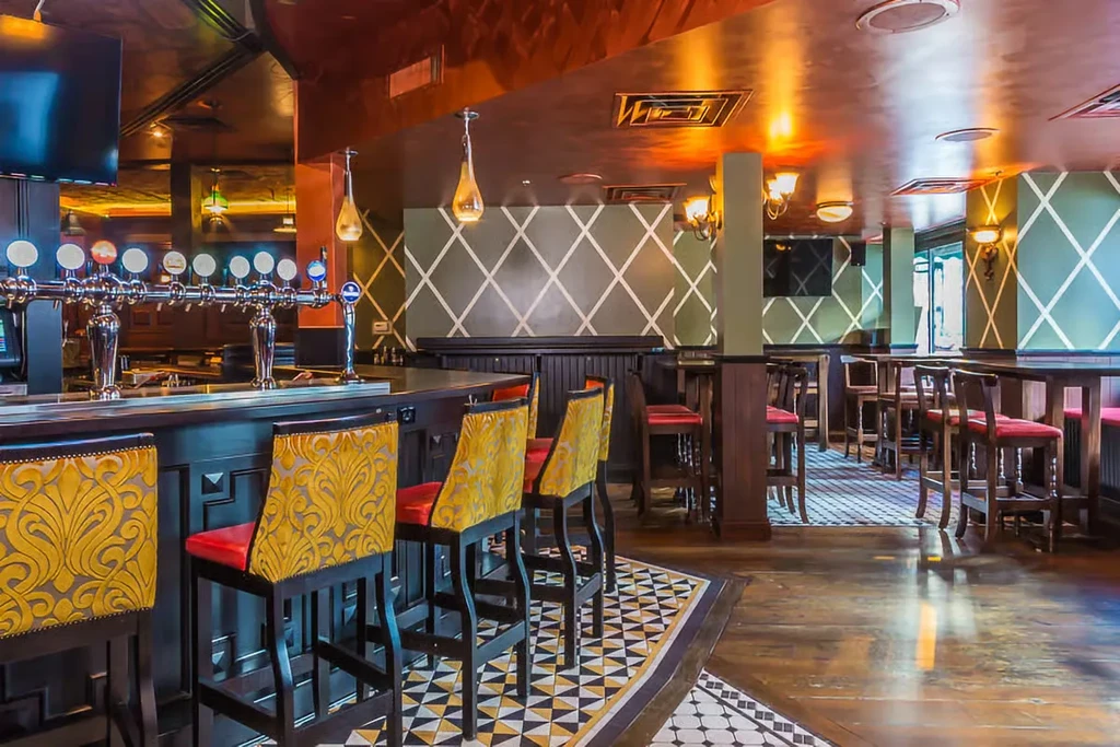 Interior of a bar with patterned stools, green walls, and geometric floor.