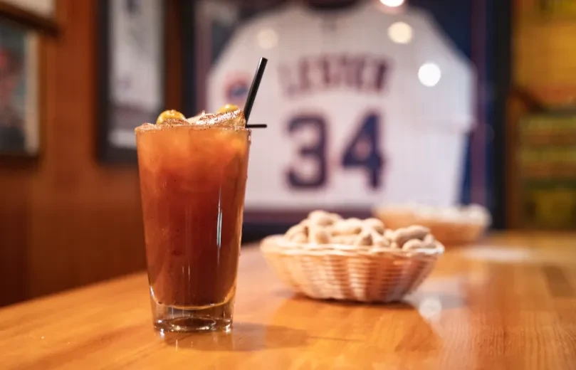 Bloody Mary cocktail with lime wedge and peanuts.