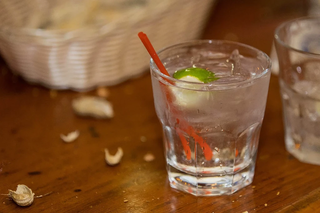 Frosted glass with a clear beverage, lime, and red straw.