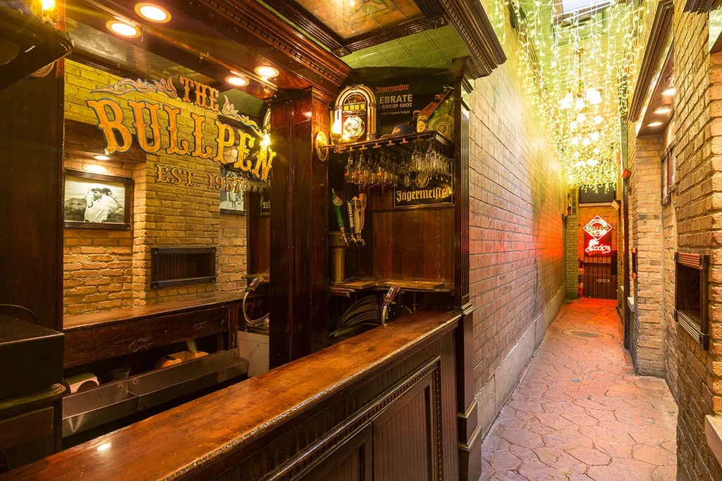 Rustic bar interior with "THE BULLPEN EST. 1957" sign.