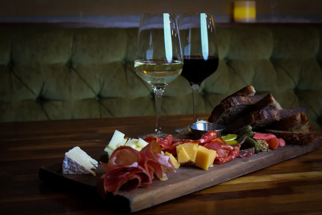 Charcuterie board with cheeses, meats, bread, and wine in a restaurant setting.
