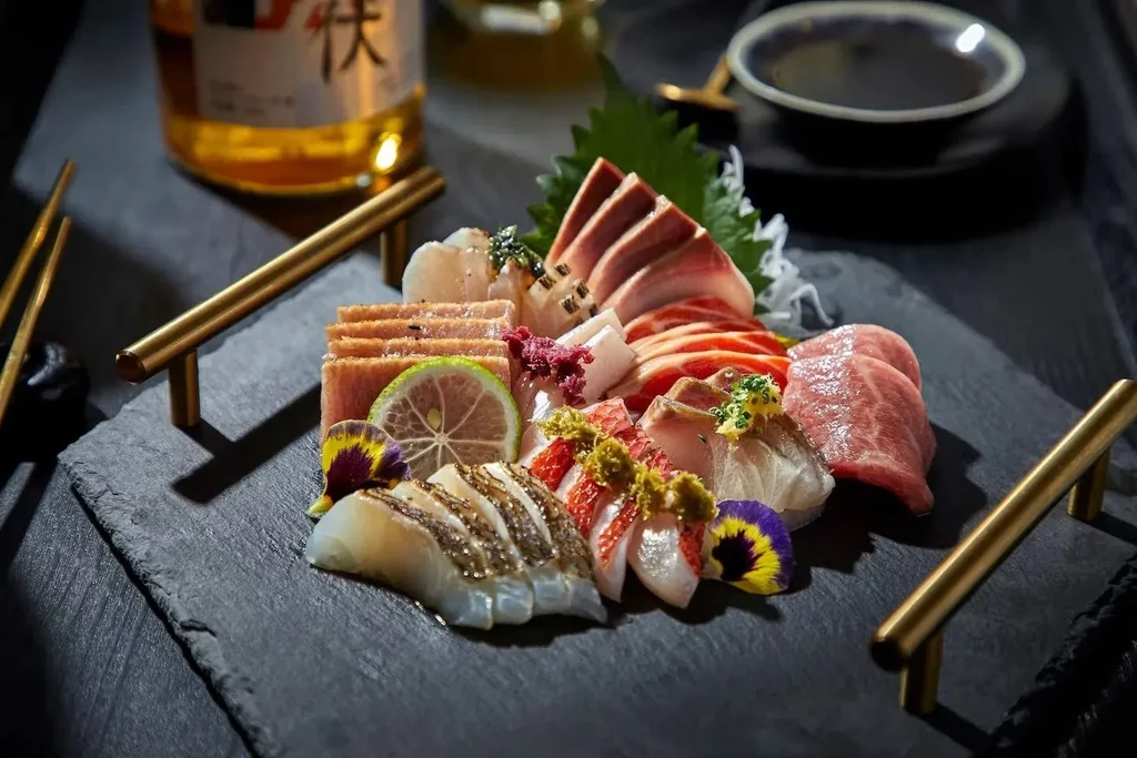 Sashimi and sushi platter with chopsticks, soy sauce, and bottle.