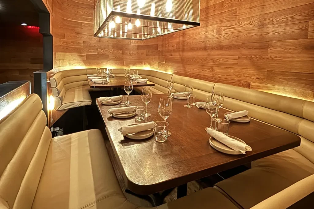 Modern restaurant interior with banquette seating and set tables.