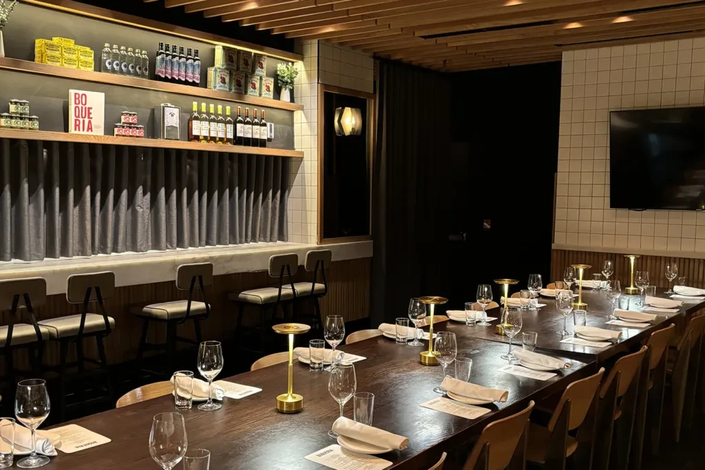 Restaurant dining table with place settings, lamps, and a bar counter.
