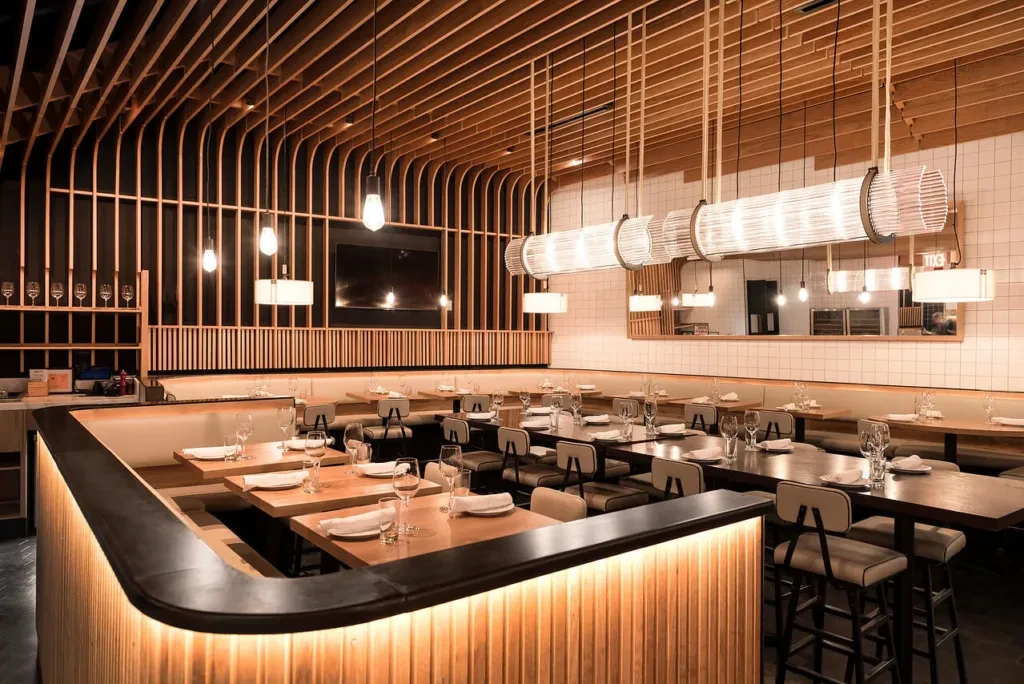 Modern restaurant interior with wooden slat walls and varied seating.