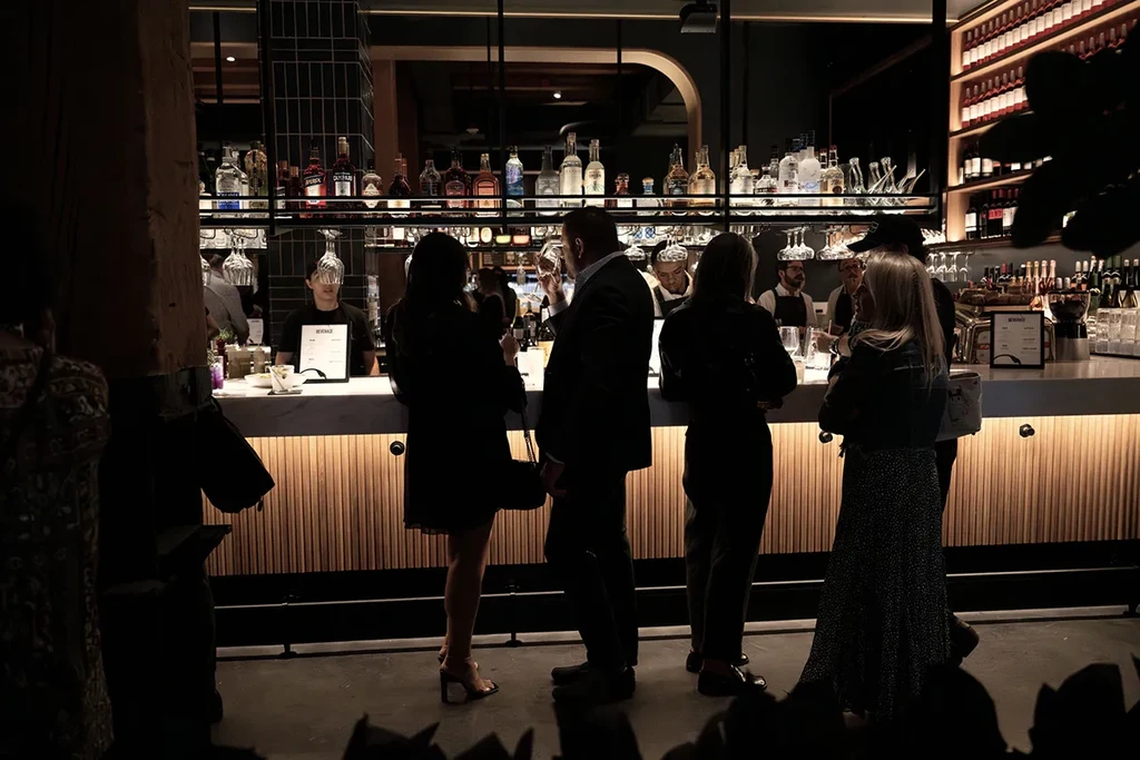 People socializing at a warmly lit, well-stocked bar.