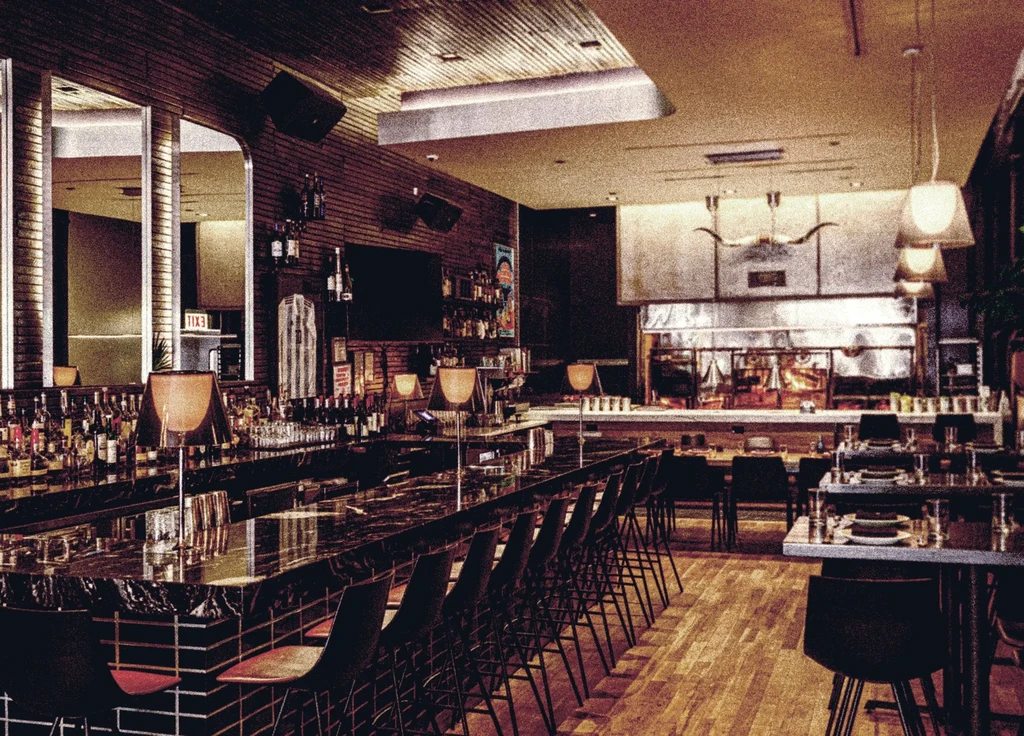 Interior of a bar and restaurant with an open kitchen.
