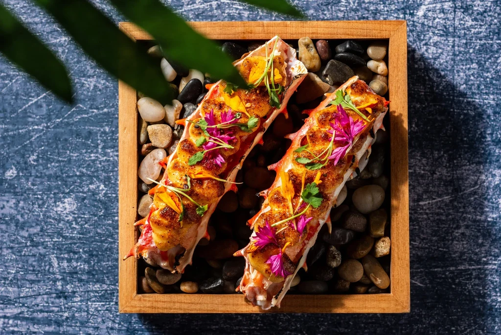 Overhead shot of two cooked king crab leg halves in a wooden tray.