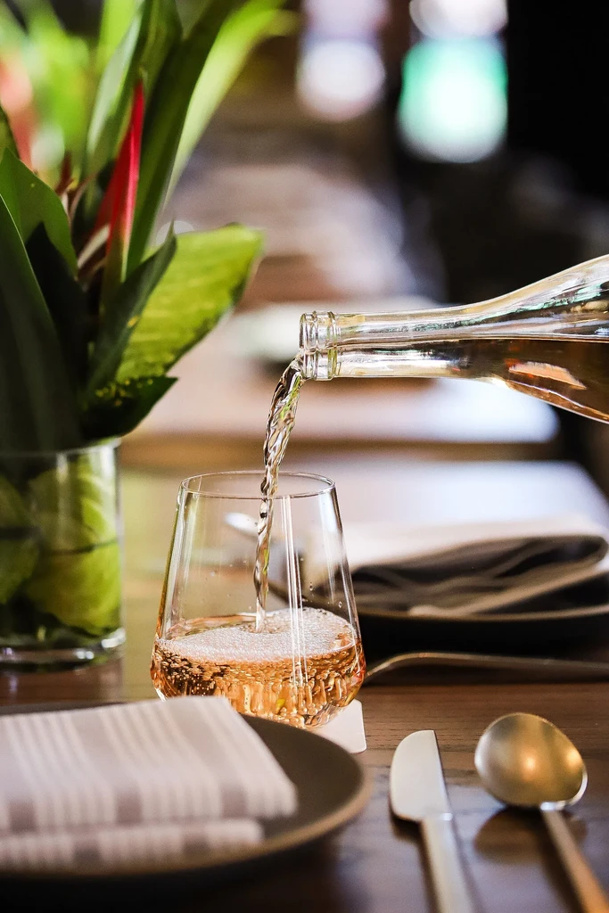 Light amber liquid pours from a bottle into a modern glass.