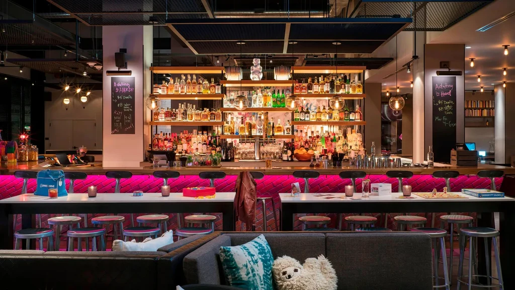 Modern bar with magenta-lit counter, liquor display, and lounge seating.