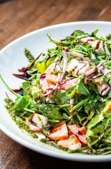 Salad with mozzarella, red onion, tomatoes, balsamic, and pesto.