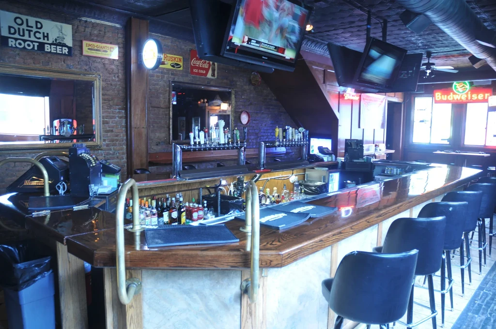 Interior of a pub with a long wooden bar and beer taps.