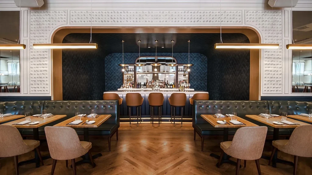 Modern restaurant interior with bar, banquettes, and elegant decor.