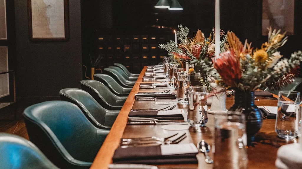 Long dining table set with floral arrangements and candles.
