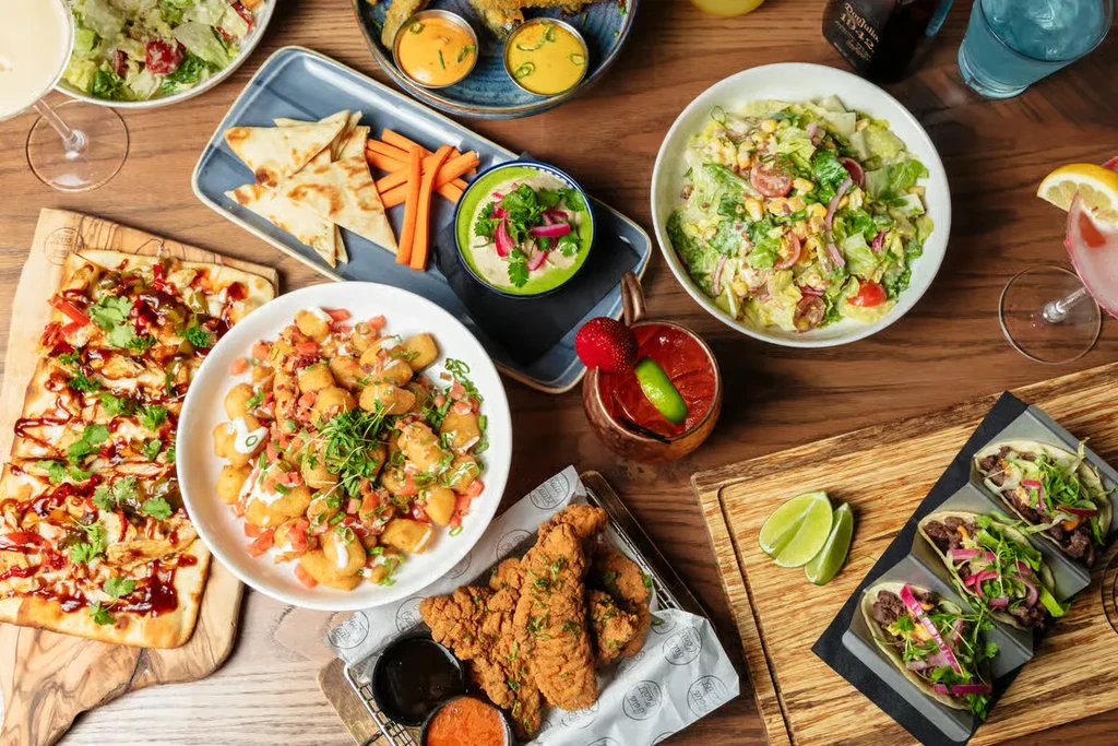 Overhead shot of a wooden table filled with food and drinks.