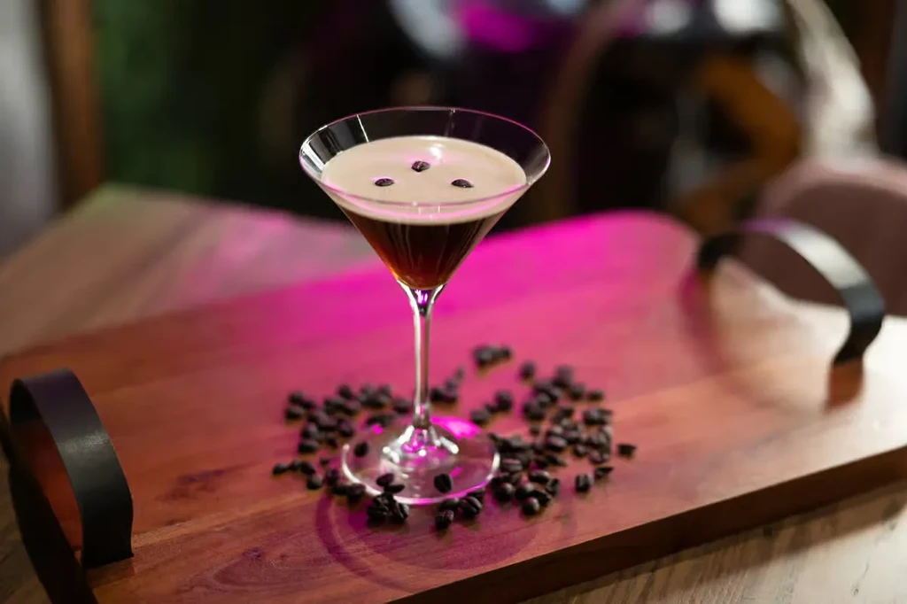 Espresso martini with coffee beans on a wooden serving board.
