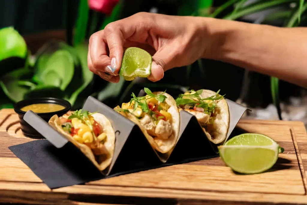 Three tacos with fresh ingredients in a metal stand.