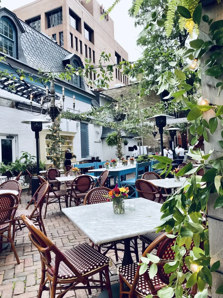 Outdoor restaurant patio with marble tables, chairs, string lights.