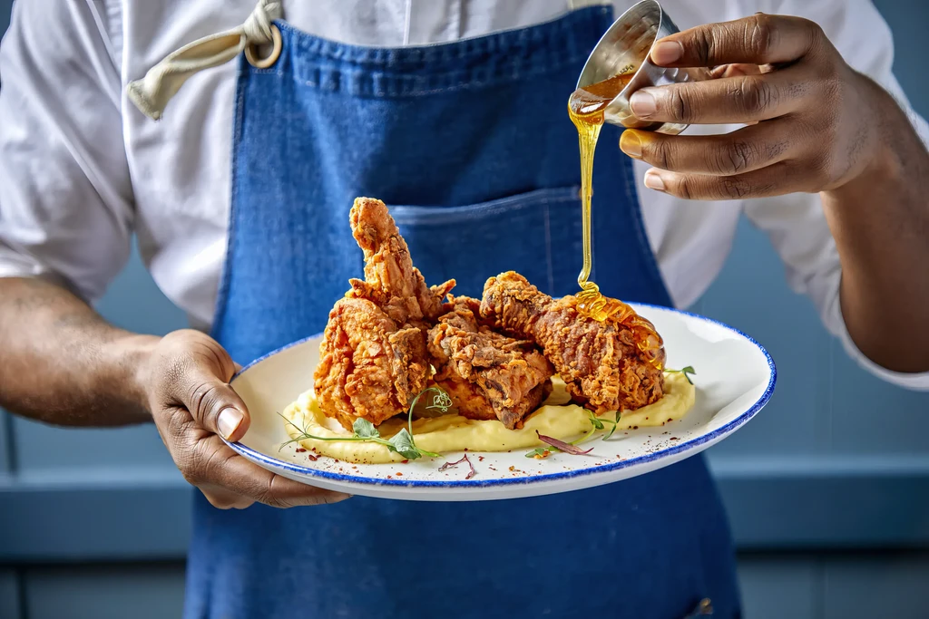 Chef serves fried chicken and mashed potatoes with sauce.