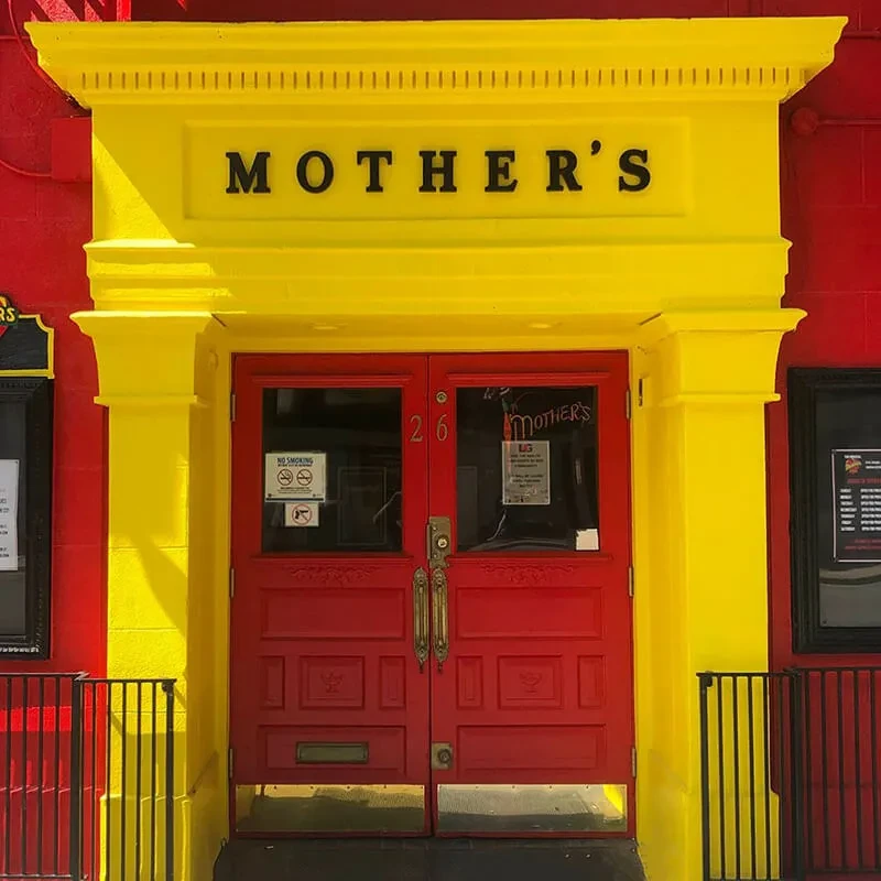 Red double doors of Mother's restaurant with a yellow archway.