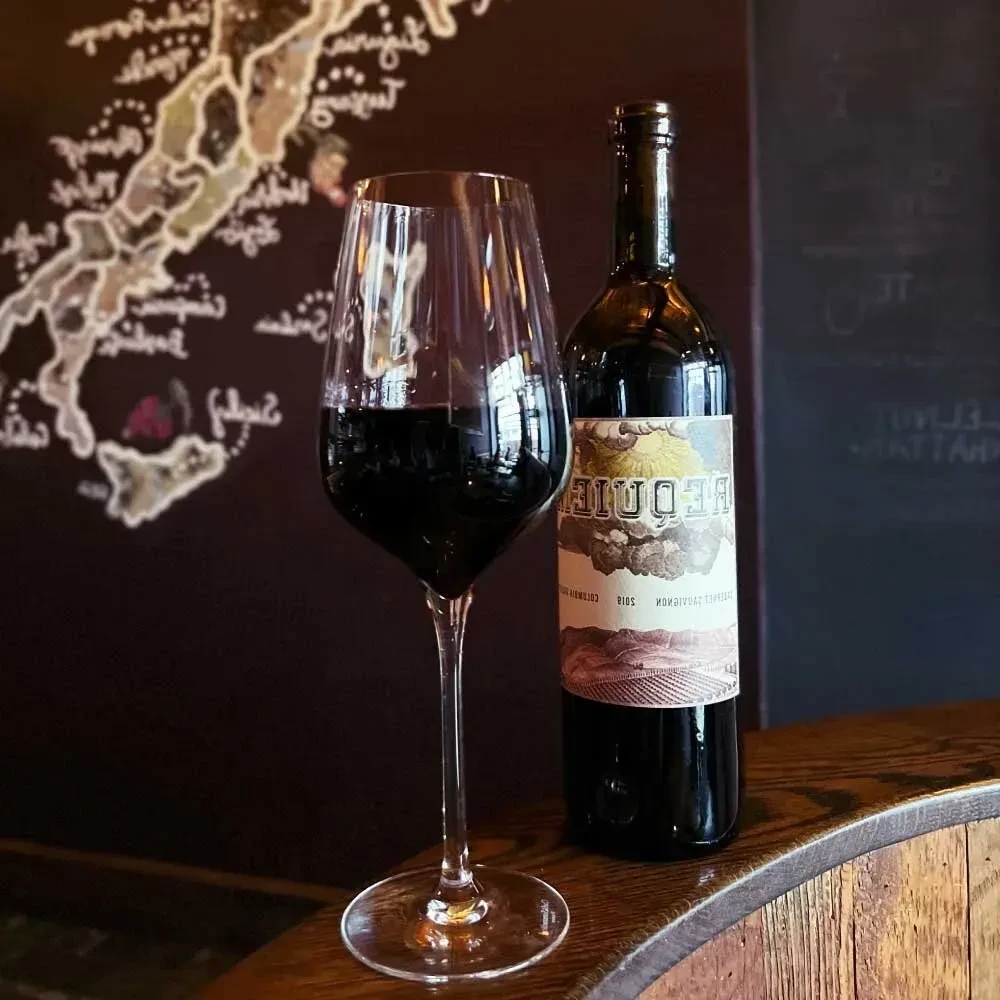 Red wine glass and bottle on a wooden surface.