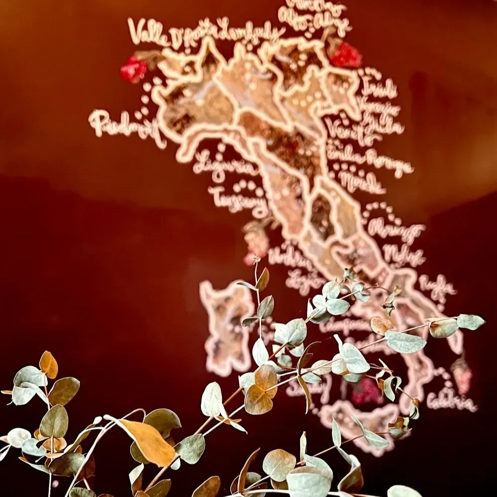 A map of Italy with regions labeled, partially obscured by eucalyptus.