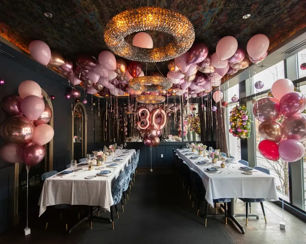 Restaurant interior decorated for a 30th celebration with pink and gold balloons.