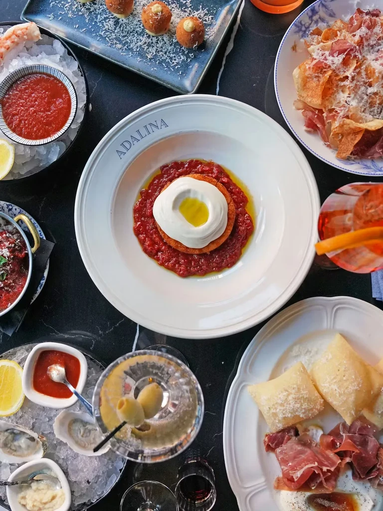 Overhead view of an Italian-inspired meal, including pasta, seafood, and drinks.