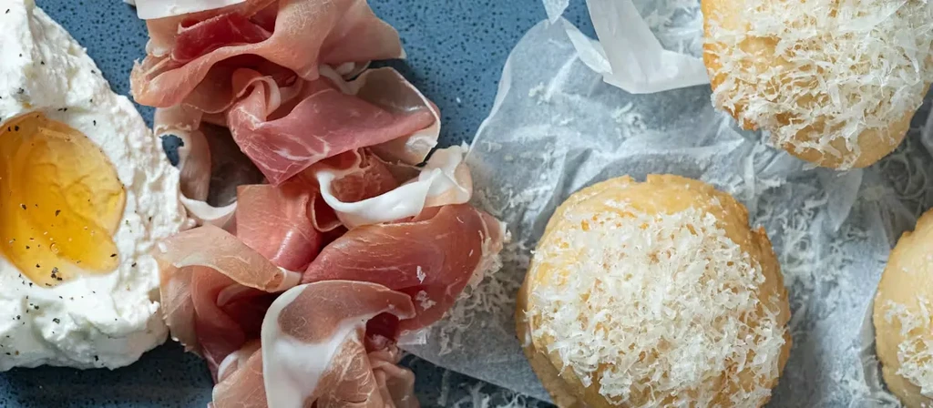 Overhead shot of charcuterie, bread, and cheese on a blue surface.