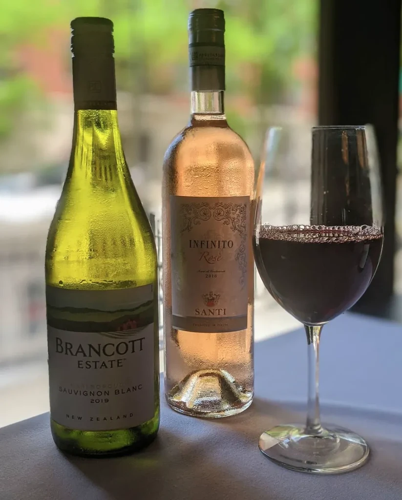 Two chilled bottles of wine and a glass of red wine.