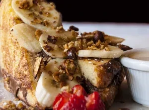 French toast topped with banana, granola, chocolate, and strawberry.