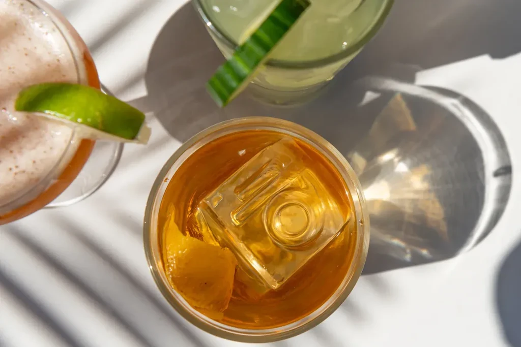 Three cocktails on a white surface, illuminated by natural light.