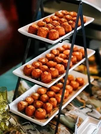 Three-tiered stand filled with golden-brown fried appetizers and orange sauce.