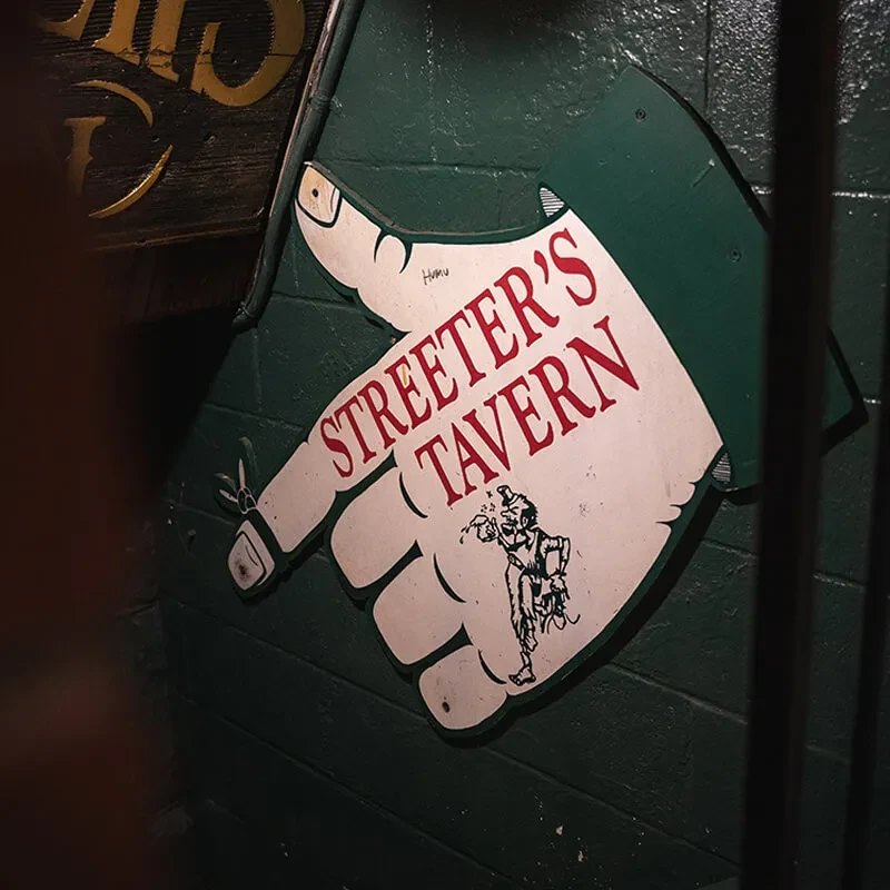 Exterior sign: a green and white hand pointing to Streeter's Tavern.